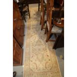 A Persian design runner with all-over scroll design on a cream ground, 125" x 30" approx