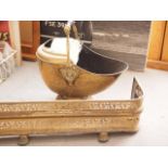 A 19th century pierced brass fender curb, 47" wide, and an embossed and engraved brass coal helmet