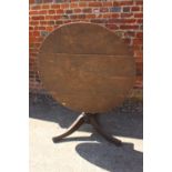 An early 19th century oak tilt top table, on turned column and tripod supports, 35" dia (top split)