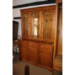 A Ducal pine dresser, the upper section enclosed three glazed panel doors over three drawers and