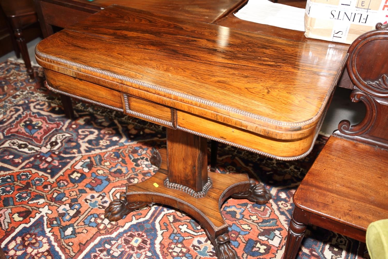 A 19th century rosewood fold-over card table, on quadraform lion claw supports, 36" wide