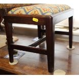 An early 19th century mahogany footstool with needlework seat, on moulded and chamfered tapering