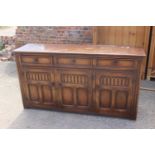 An oak dresser base, fitted three drawers over arcade carved doors, on stile supports, 62" wide x