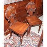 A pair of early 19th century Cuban mahogany hall chairs with shield inset backs, on turned supports