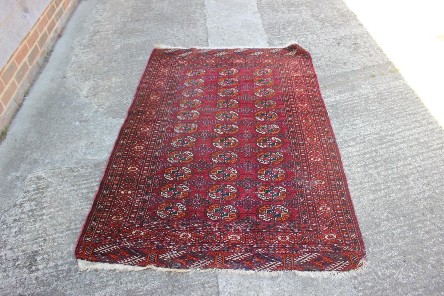 A Bokhara rug with thirty-three guls on a red ground with multi-borders in shades of green, orange