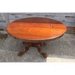 A 19th century mahogany circular tilt top dining table, on turned column and carved quadruple