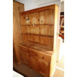 A pine dresser, fitted open shelves over three drawers and cupboard, on bracket feet, 47" wide x 18"