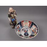 A Japanese Imari bowl with traditional design and a Japanese porcelain figure of a man with stool,