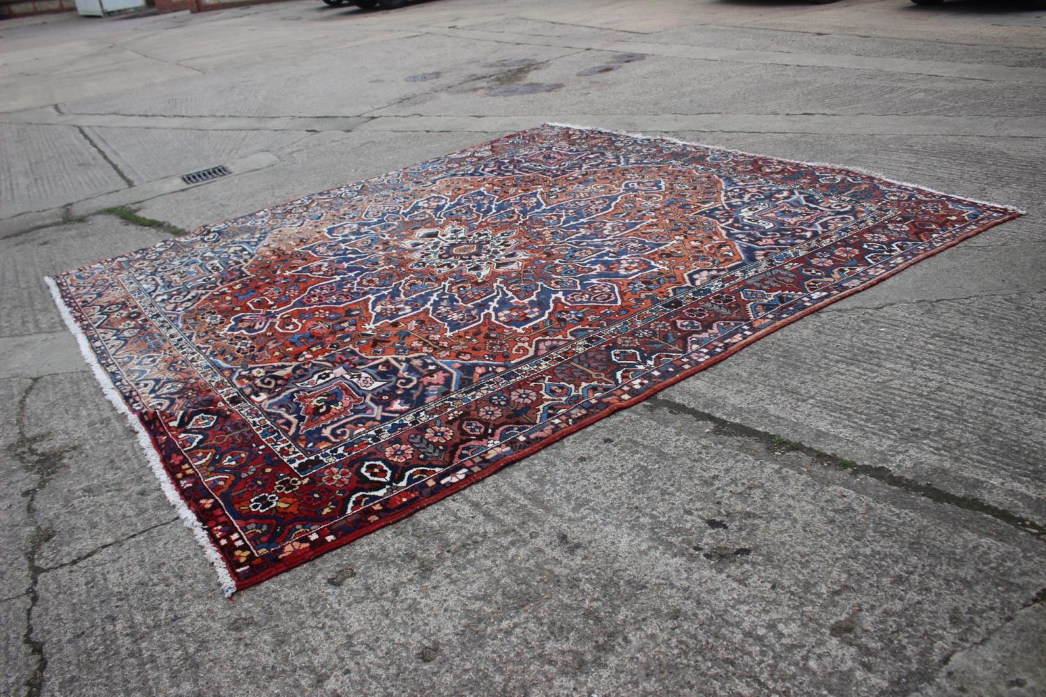 A Hamadan carpet with central star design, on a salmon ground, in shades of blue, brown, pink,
