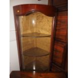 An early 20th century hardwood bowfront corner display cabinet with frosted glass shelves and rear