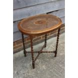 A mahogany oval occasional table with rattan top, on barley twist supports united by an 'X'