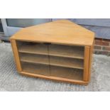 An Ercol elm corner television stand, fitted two shelves and glass doors, 36" wide