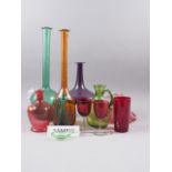 Six cranberry coloured glasses, two similar jugs, two long necked green glass bottles (tallest 17