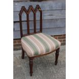 A carved oak gothic design side chair with triple arch back, seat upholstered in a striped fabric,