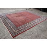 A Persian carpet with all-over boteh design on a red ground, multi-bordered in shades of blue,