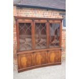 A figured mahogany concave bookcase of Georgian design enclosed three Gothic glazed panel doors over