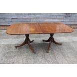 A mahogany double pedestal dining table with extra leaf, on twin turned columns and tripod splay