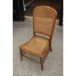 A late 19th century polished as satinwood cane seat and back low seat nursing chair, on turned and
