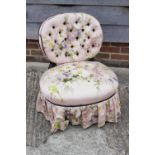 A 19th century ebonised frame low seat nursing chair, button upholstered in a floral fabric, on