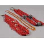 A coral and semi-precious stone beaded necklace, another similar and an amber beaded necklace