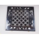 A Japanese? ebonised and mother-of-pearl inlaid chess and backgammon board, 25" wide