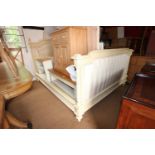 A Louis XVI design cream painted bed frame with flanking columns, padded head and foot boards, and