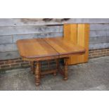 A French light oak extending dining table with two extra leaves, on turned supports and shaped base,