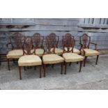 A set of eight mahogany standard dining chairs with pierced shield-shaped splay backs and stuffed