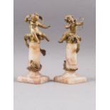 A pair of gilt metal and alabaster amorini, on columns, 9" high (one arm damaged)