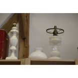 An assortment of light fittings, including a brass oil lamp, ceiling lights and a white glass oil