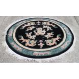 A Chinese circular contour pile rug with dragon design on a black ground, 88" dia
