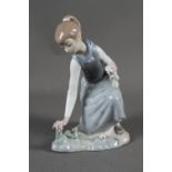 A Lladro ceramic figure of a young girl picking flowers, 8 1/2" high