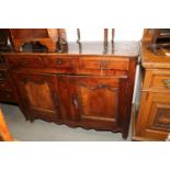 A Continental oak sideboard, fitted three drawers over two cupboards with fielded panels, on