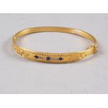 A Victorian gilded 15ct gold hinged bangle, set three sapphires and eight diamonds