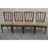 A set of four early 19th century fruitwood dining chairs with swag carved vertical rail backs and