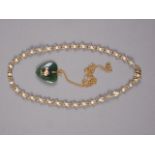 A 9ct gold chain with nephrite heart-shaped pendant, set with yellow metal model of a kiwi, and