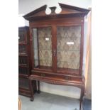 A William Kent design carved mahogany display cabinet with broken pediment, over two glazed doors