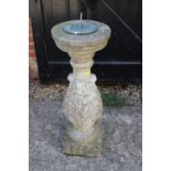 A cast stone sundial pillar with acanthus leaf decoration and a brass sundial