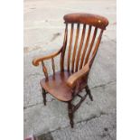 A Windsor lath back elbow chair with panel seat, on turned and stretchered supports