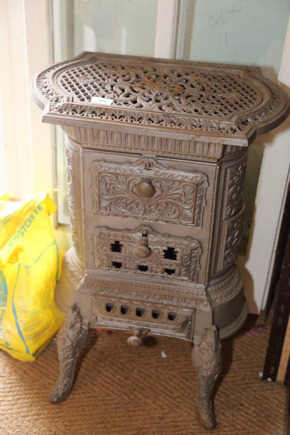 A grey painted cast iron stove with pierced decoration, on cabriole supports, 19" wide x 13" deep