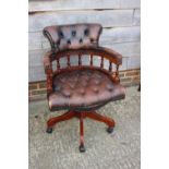 A polished as mahogany spindle back desk elbow chair, button upholstered in a brown leather, on