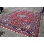 A Persian carpet with central medallion, floral and bird designs on a red ground, in shades of