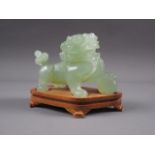 A Chinese carved green jade model of a Dog of Fo, on hardwood stand, 3 1/2" high overall