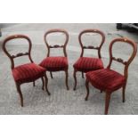 A set of four late 19th century walnut loop back dining chairs with stuffed over seats,