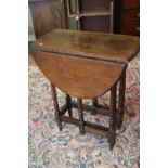 An oak oval drop leaf gateleg table, on turned and stretchered supports, 25 1/2" wide x 35" deep x