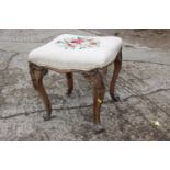 A 19th century carved walnut stool with needlework seat, on cabriole scroll supports