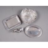 An embossed silver heart-shaped sweetmeat dish, an oval pin tray, a rectangular pin tray, a model