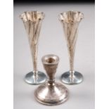 A pair of planished silver trumpet vases with loaded bases and a sterling silver candlestick (