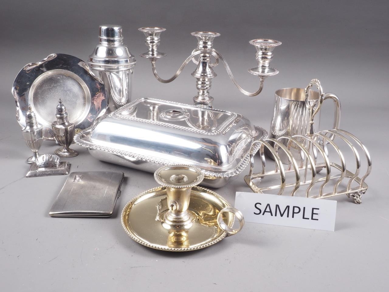 A pair of silver plated entree dishes and covers, a pair of plated three-branch candelabra, a plated