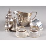 A silver cream jug, three silver pepper shakers, a silver napkin ring and a pair of silver mounted
